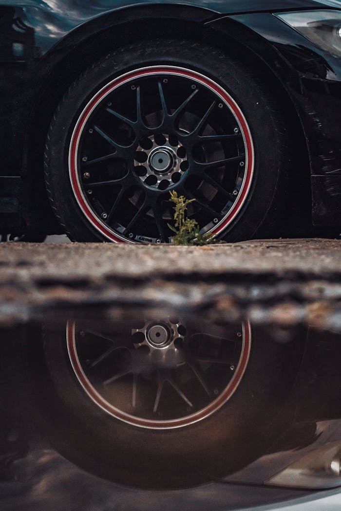 Dramatic shot of a car wheel with reflection in a puddle, emphasizing style and technology.